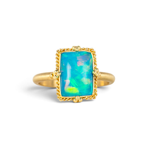 A handmade gold ring featuring an Ethiopian opal gemstone, against a white backdrop.