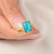 A handmade gold ring featuring an Ethiopian opal gemstone, held in a hand.