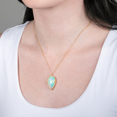 Ethiopian opal pendant necklace with 18k gold bezel on a person