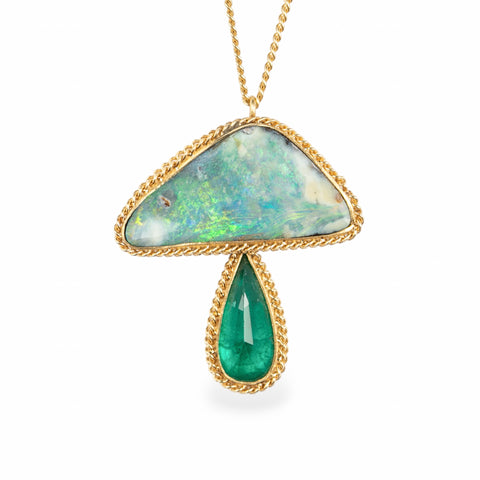 Gold necklace with a mushroom pendant featuring an emerald and opal stone on a white background