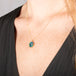 Handmade opal doublet pendant necklace featuring a carved hummingbird on a gold chain on a person