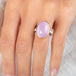A ring featuring a large oval kunzite stone, set in a gold textured bezel with a sterling silver band, worn on a person's finger.