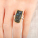 Close up of a person wearing a handmade fine jewelry labradorite owl ring set in 18k gold with a sterling silver band
