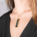 Handcrafted gold necklace with a labradorite gemstone pendant worn by a person against a neutral background.