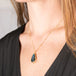 Necklace with a labradorite pendant worn by a person against a neutral background