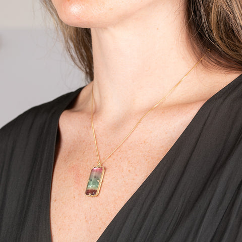 Handmade necklace with a watermelon tourmaline gemstone set in a gold bezel on a person