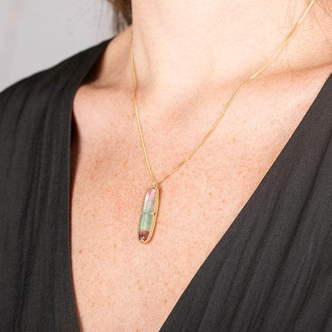 Handmade necklace with a watermelon tourmaline gemstone set in a gold bezel on a person