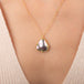 Gold necklace featuring a mabe pearl stone worn on a person's neck.