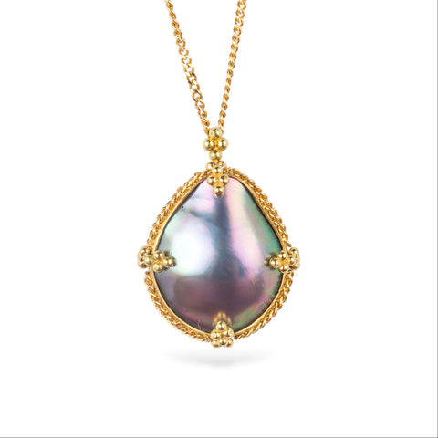 Gold necklace featuring a mabe pearl set in a handcrafted 18k gold bezel, against a white backgorund.