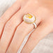 Close up of someone wearing a ring with a Mexican opal stone, gold bezel and sterling silver band on a white background