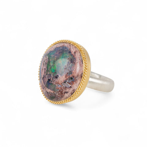 Ring with a mexican opal stone and 18k gold bezel with a sterling silver band on a white background
