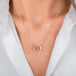 A gold necklace featuring a moonstone gem, worn on a person's neck.