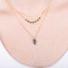A model wears an 18k gold and blue diamond chain necklace paired with a small carved leaf moonstone necklace.