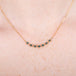 A close up of a model wearing an 18k gold and blue diamond chain necklace.
