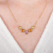 A gold necklace featuring a row of sapphire gemstones in different shapes and colors, shown worn on a model's neck.