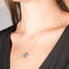 Handmade 18k yellow gold necklace featuring an opal doublet with a carved hummingbird worn by a person