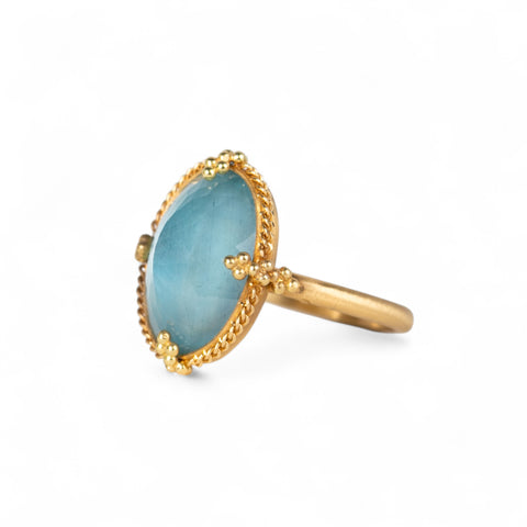 Handcrafted 18k gold ring with a blue aquamarine gemstone on a white background.