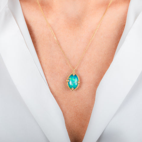A gold necklace featuring an oval Ethiopian opal gemstone, shown worn on a model's neck.