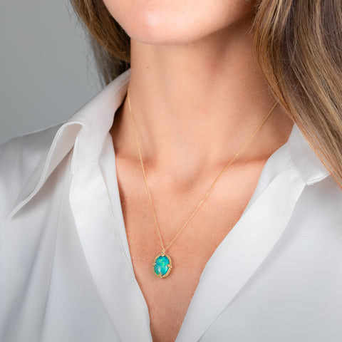 A gold necklace featuring an oval Ethiopian opal gemstone, shown worn on a model's neck.