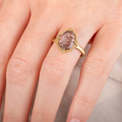 A model wears a handmade 18k yellow gold and super 7 gemstone ring.