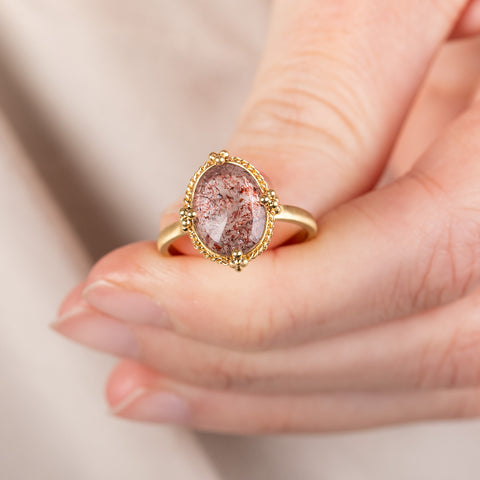 Handmade 18k gold and Super 7 gemstone ring held in hand.