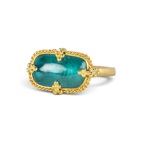 Gold ring featuring a teal pariba kyanite stone set in an 18k gold bezel, shown against a white background.