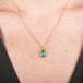 Handcrafted gold necklace with a one-of-a-kind emerald teardrop pendant on a model's neck.