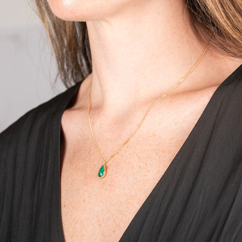 Handcrafted gold necklace with a one-of-a-kind emerald teardrop pendant worn by a model.