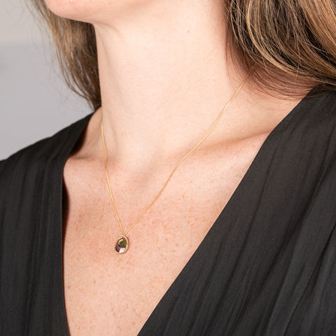 Handmade necklace featuring a watermelon tourmaline gemstone set in a 18k gold bezel on a person