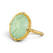 A gold ring featuring a prehnite with a fairy design carved in it, shown against a white background.