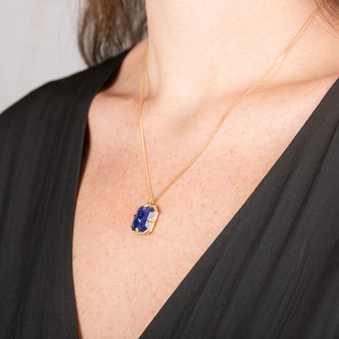Handmade gold necklace with a blue tanzanite gemstone pendant on a person