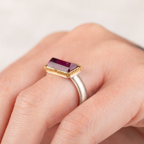 Close up of a hand wearing a Tourmaline ring with gold bezel and silver band
