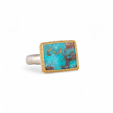 Turquoise ring with gold bezel and silver band on white background