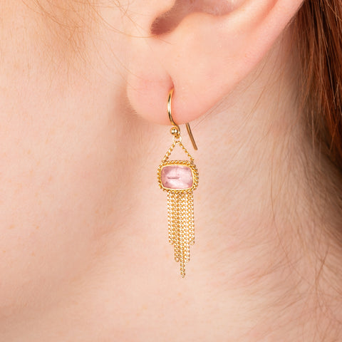 Gold earrings featuring rhodochrosite gemstones and gold chain tassels, shown worn in a person's ear.