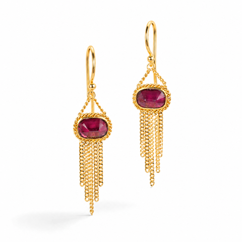 Gold earrings featuring rhodolite garnet gemstones and gold chain tassels, shown against a white background.