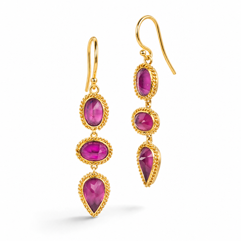 Gold earrings featuring a trio of vibrant red-pink rhodolite garnet gemstones, shown against a white background