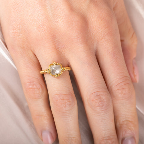 Gold ring with a silver diamond on a person's finger