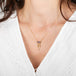 Gold necklace with a a spessartite gemstone adorned with a gold tassel on a person wearing a white top.