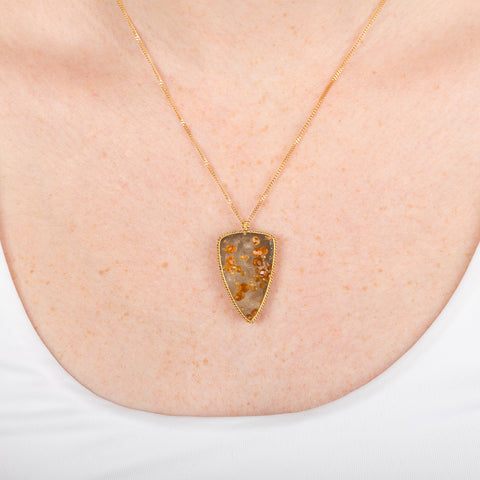 Gold necklace featuring spessartite garnet in quartz on a person