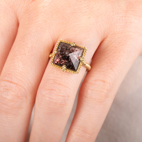A model wears an 18k yellow gold and super 7 gemstone ring.