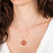 Necklace with a round sunstone pendant carved as a sun face worn by a person