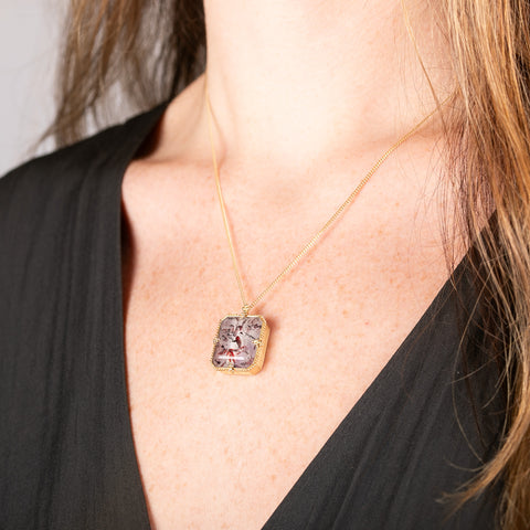 Handmade gold necklace with a Super 7 gemstone on a person