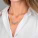 A gold necklace featuring five tanzanite gemstones in textured gold bezels, worn on a model's neck.