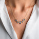 A gold necklace featuring five tanzanite gemstones in textured gold bezels, worn on a model's neck.