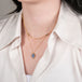 Gold necklace with a leaf-shaped tanzanite pendant on a person.