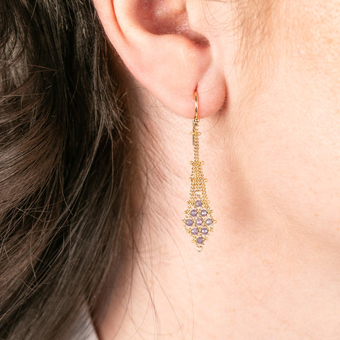 Gold earring with tanzanite stones worn by a person
