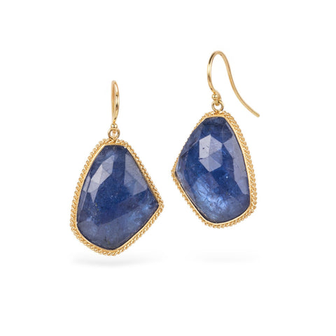 Pair of blue tanzanite earrings with gold settings on a white background