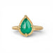 Gold ring with a teardrop-shaped emerald gemstone on a white background