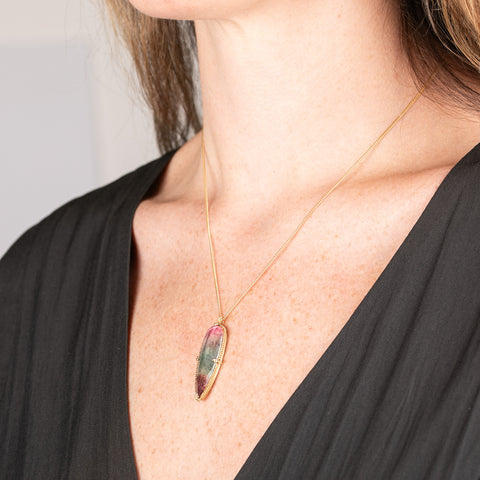 Handmade gold necklace with a watermelon tourmaline gemstone pendant on a person