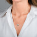 A gold necklace featuring a teardrop-shaped aquamarine necklace, shown worn on a model's neck.